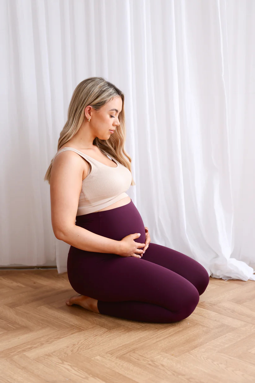 SeamlessLuxeLeggingsPlum_4 Model wearing plum Seamless Luxe Maternity Leggings in a side pose.